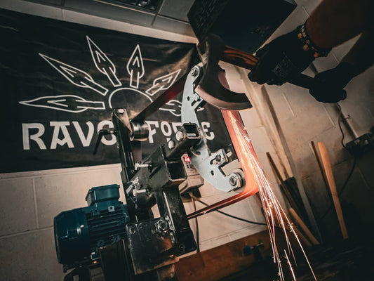 Grinding a blade edge on a belt grinder in the Raven Forge workshop