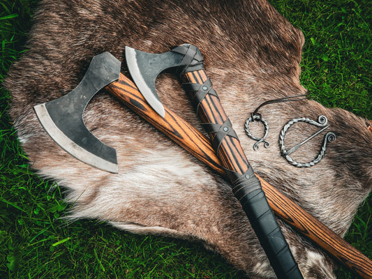 Two Viking axes and iron cloak pins laid on a fur throw