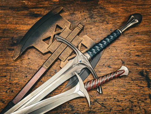 Fantasy film sword replicas and a bronze axe on a wooden table