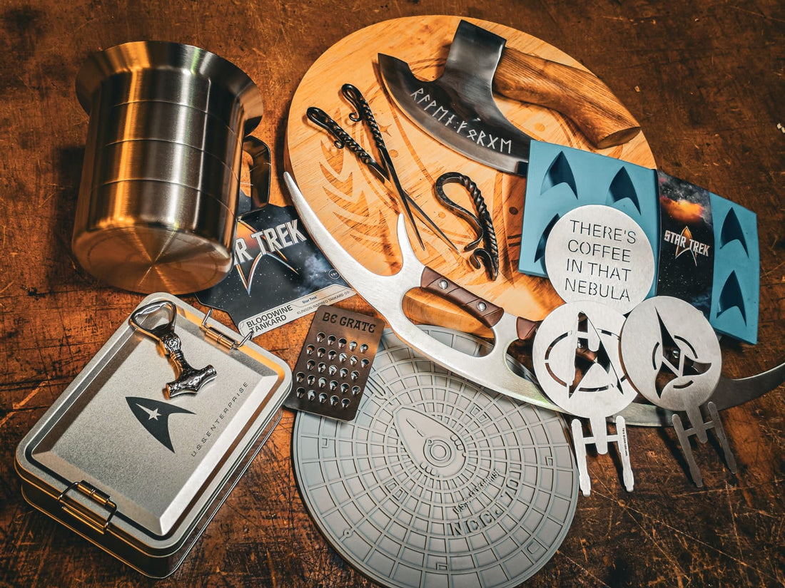 Star Trek kitchenware including a tankard, bat'leth-style pizza cutter, cheese grater, coasters and a runic axe on a wooden board