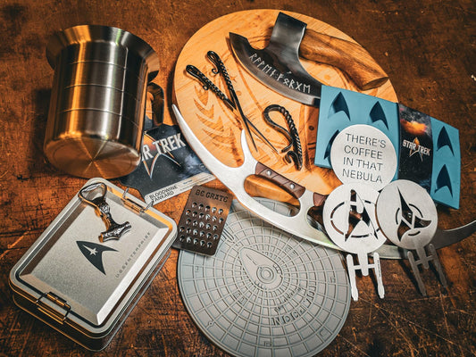 Star Trek kitchenware including a tankard, bat'leth-style pizza cutter, cheese grater, coasters and a runic axe on a wooden board
